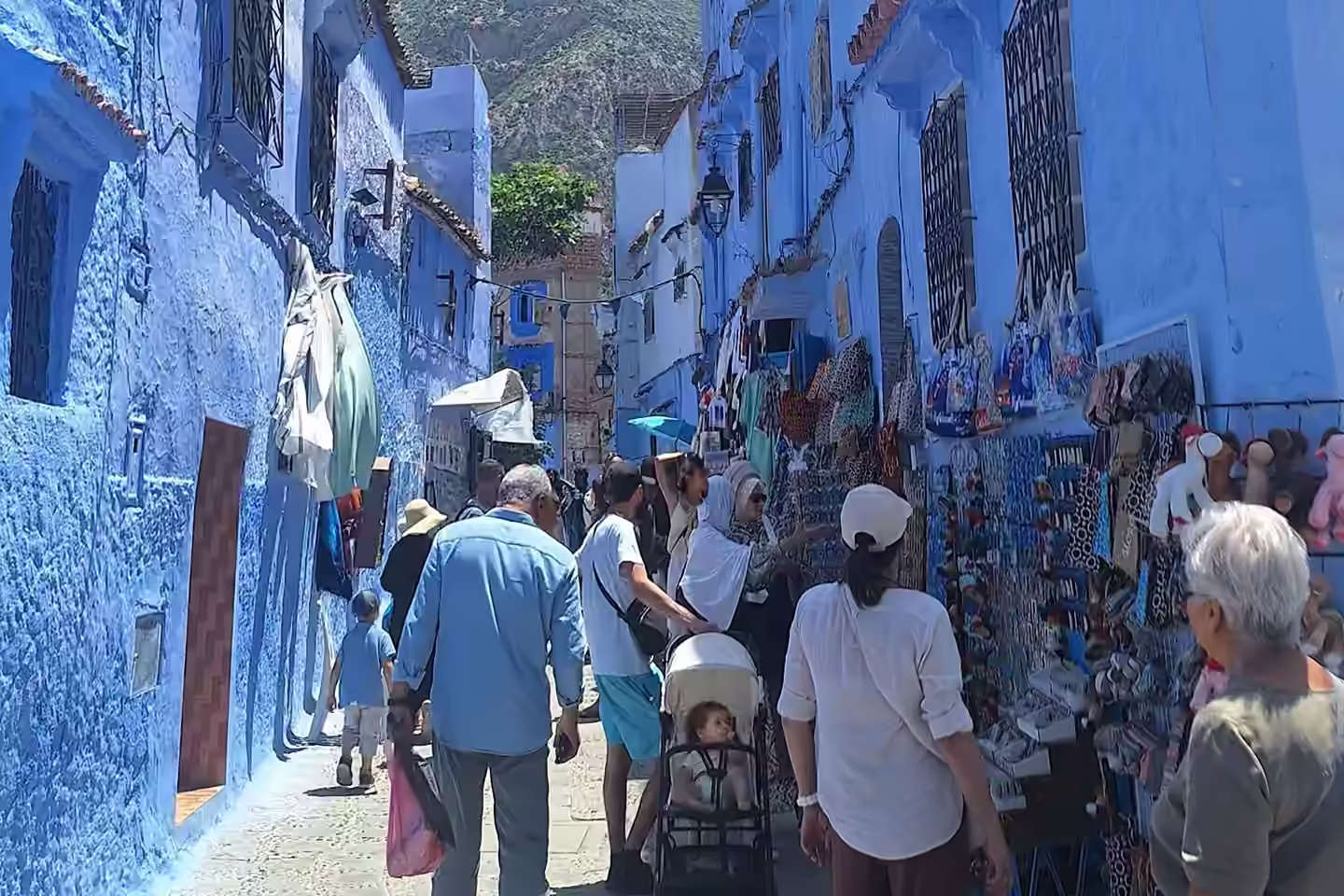 Des passants dans une ruelle bleue animée de la médina de Chefchaouen