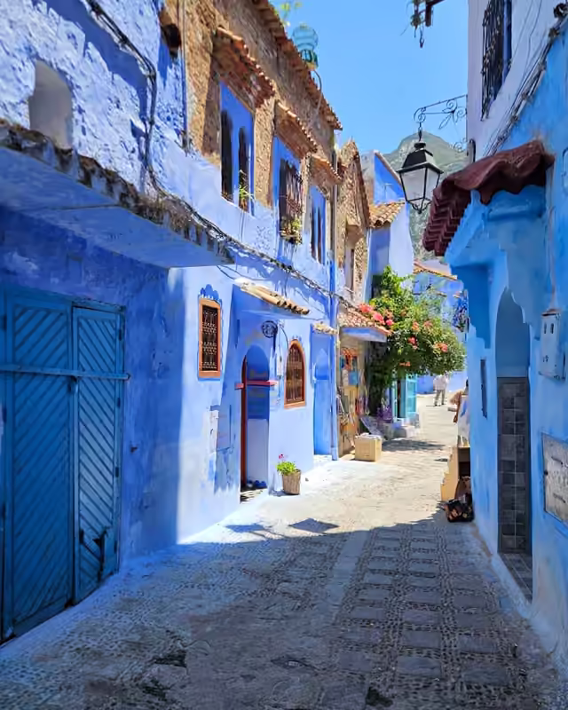 A blue alley with bougainvillea and a lantern in Chefchaouen