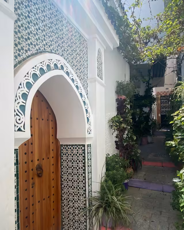 A carved and tiled doorway in a white Tangier medina lane