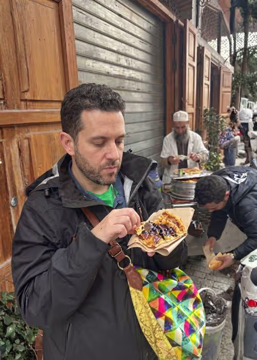 A traveler eating a street food sandwich in the Tangier medina