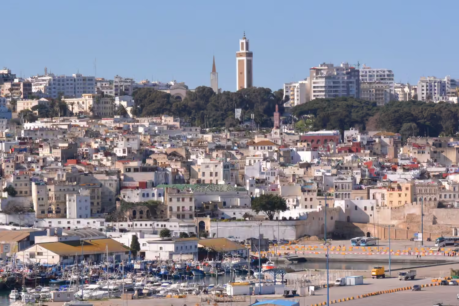 Les maisons blanches de la médina de Tanger au-dessus du port, avec des bateaux en bas et un minaret
