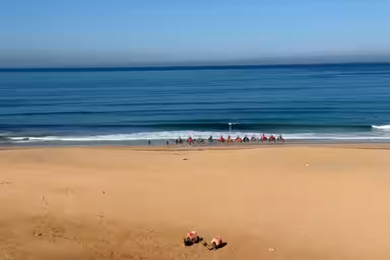 Camellos caminando por la playa atlántica cerca de las Cuevas de Hércules