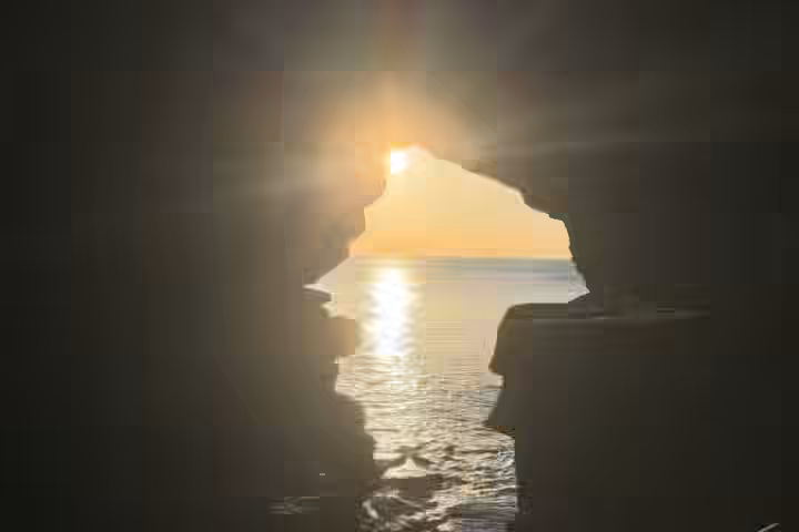 El sol poniente enmarcado por la abertura al mar de las Cuevas de Hércules
